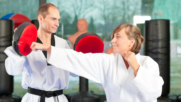 A man and a woman are practicing martial arts in a gym.