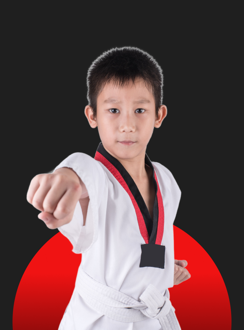A young boy in a karate uniform is pointing at the camera