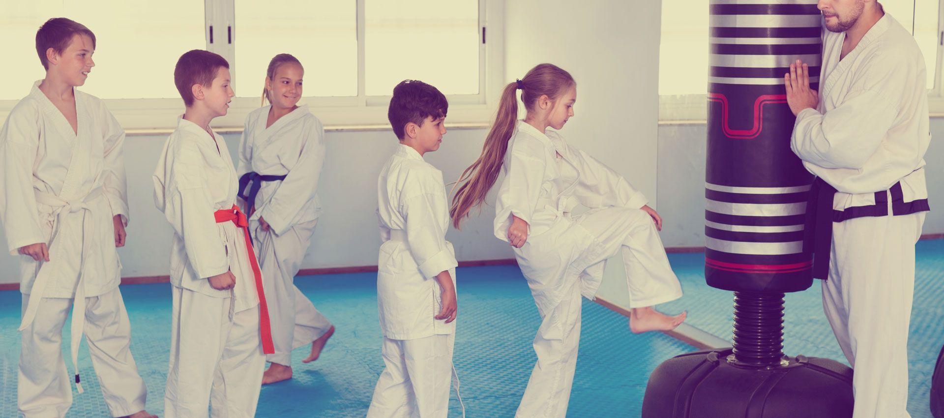 A group of children are practicing karate in a gym.