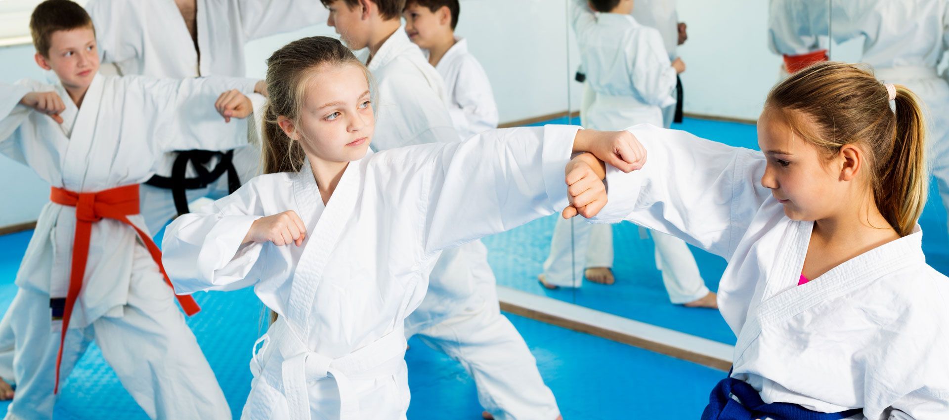 A group of children are practicing karate in a gym.