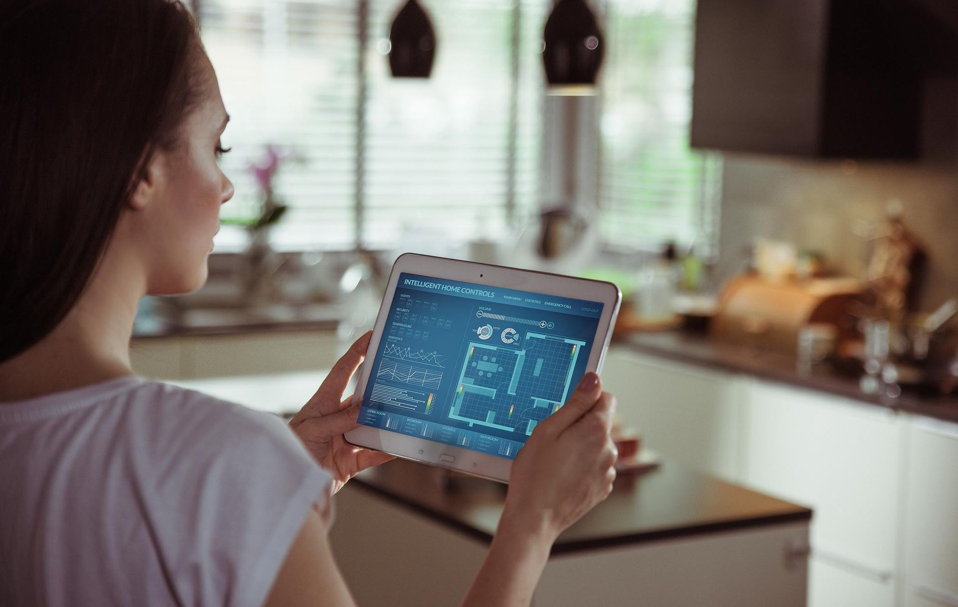 A woman is holding a tablet in her hands in a kitchen.
