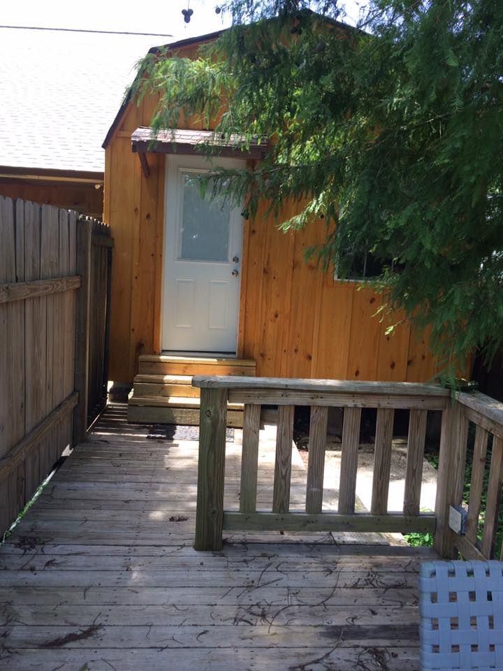 A small wooden house with a wooden deck in front of it