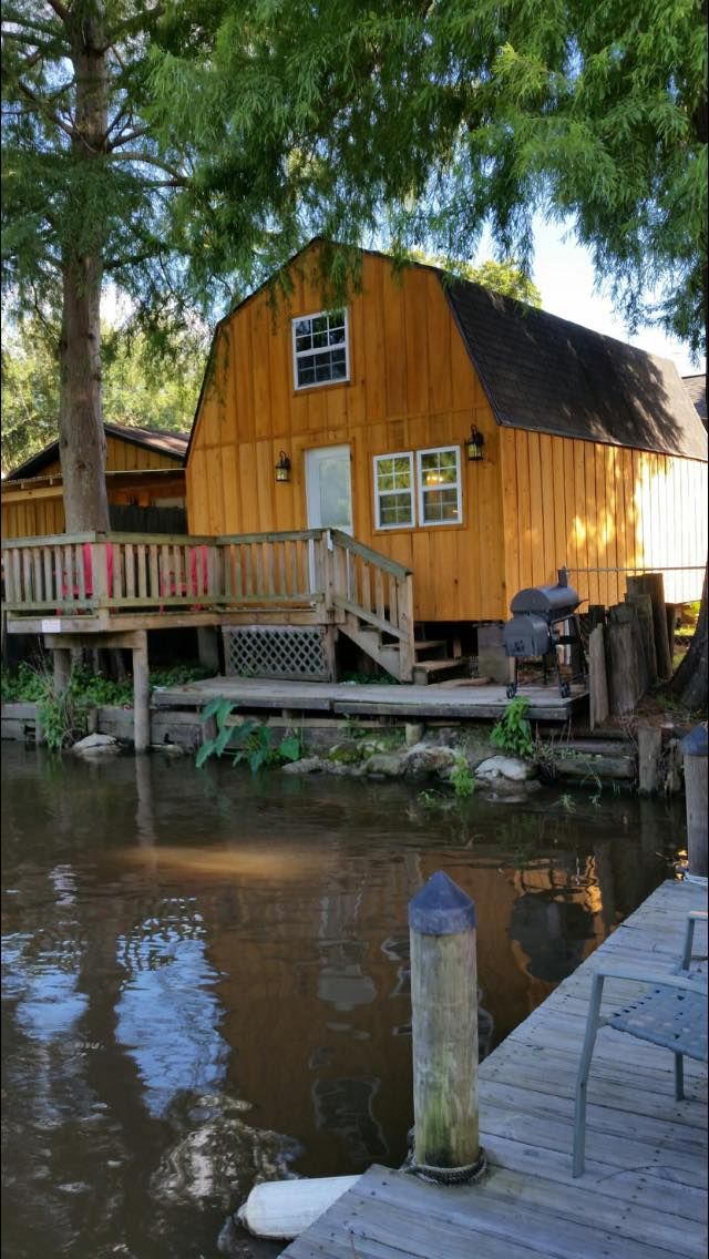 A wooden barn with a dock in front of it next to a body of water.