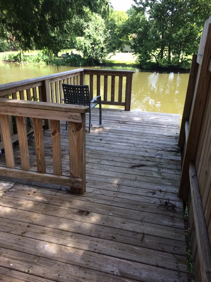 A wooden deck overlooking a lake with a chair on it
