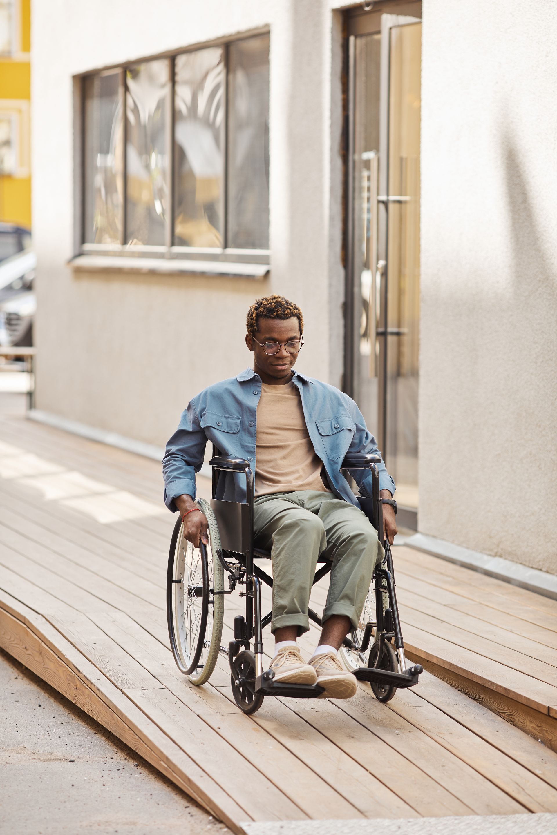 A man in a wheelchair is sitting on a wooden ramp.