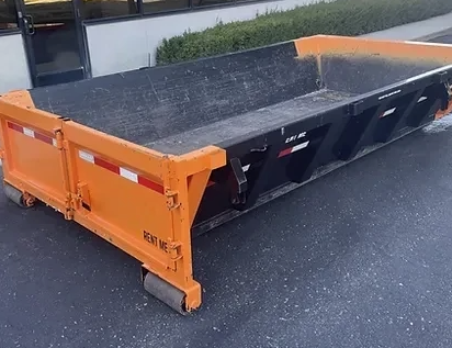 Orange and black dumpster on pavement; 