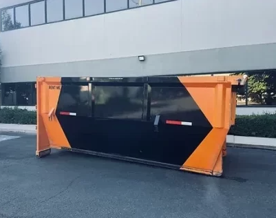 Orange and black dumpster in front of a building.
