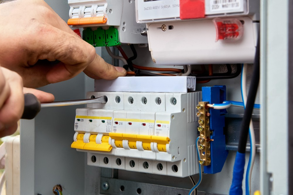 a person is working on an electrical box with a screwdriver .