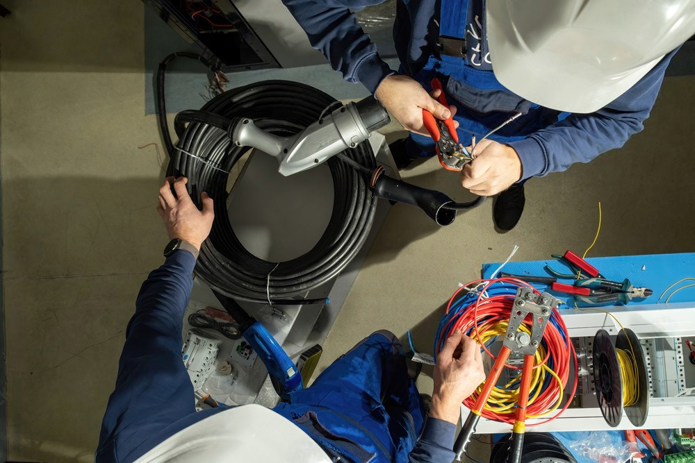 two men are working on electrical wires in a room .