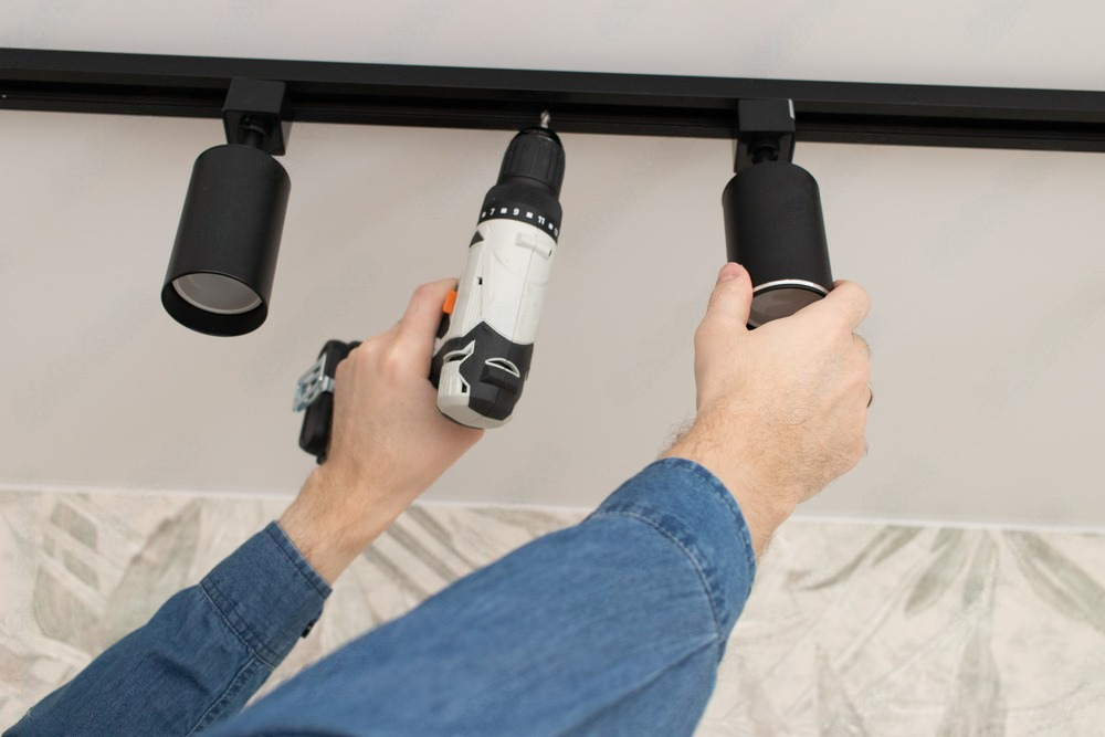 a person is installing a ceiling light with a drill .