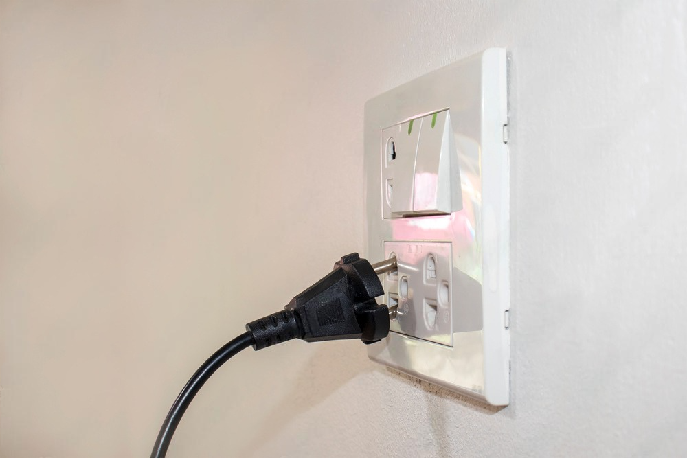 a plug is plugged into a light switch on a wall .