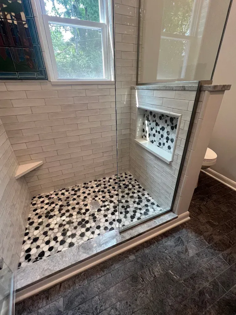 A bathroom with a walk in shower and a window.