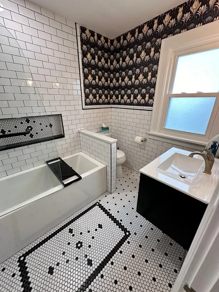 A bathroom with a tub , sink , toilet and window