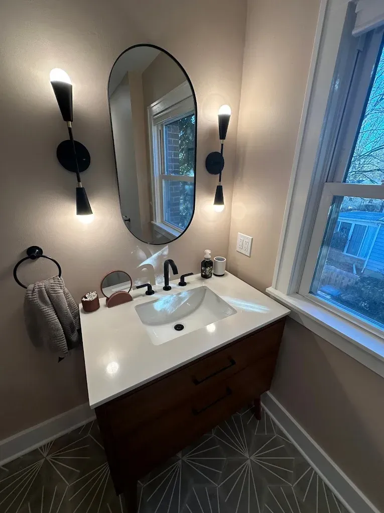A bathroom with a sink , mirror and window.