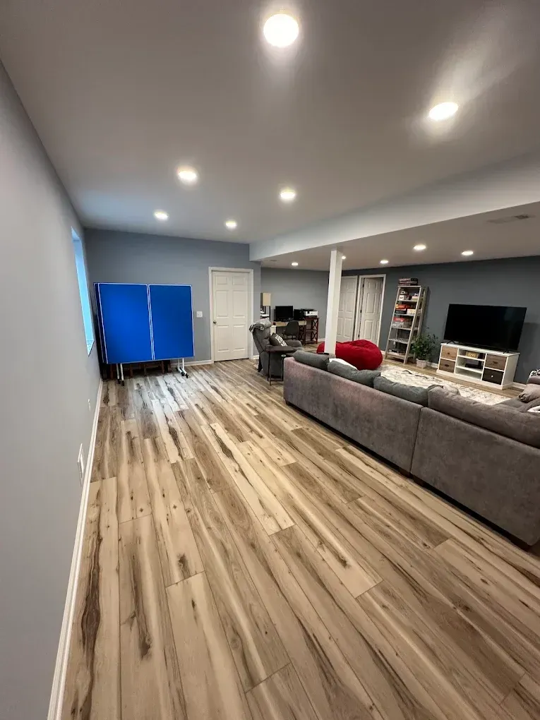 A living room in a basement with hardwood floors and a couch.