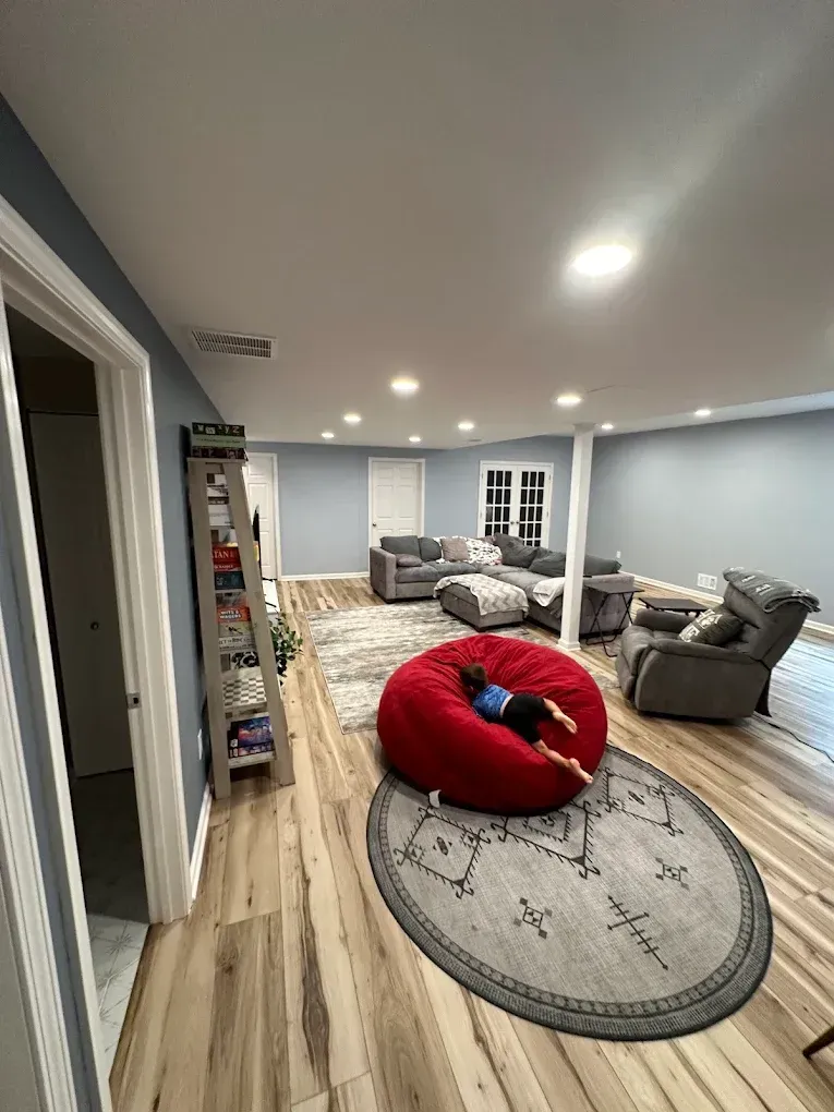 A person is laying on a red bean bag chair in a living room.