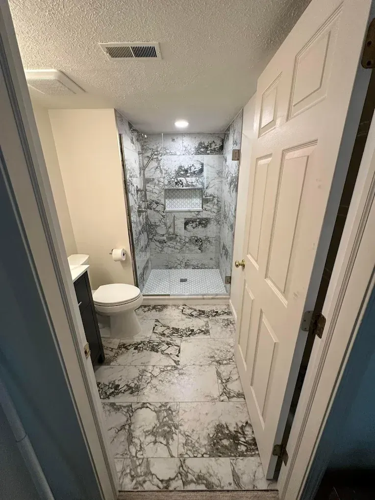 A bathroom with a toilet , sink and walk in shower.