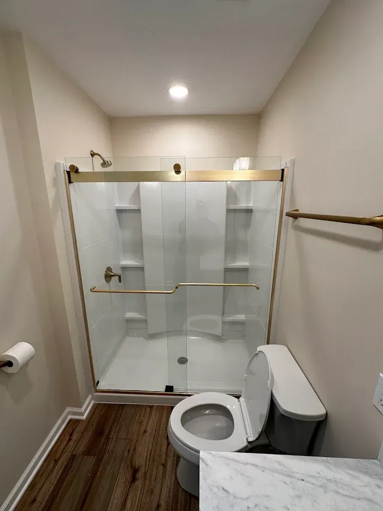 A bathroom with a toilet , shower , and sink.