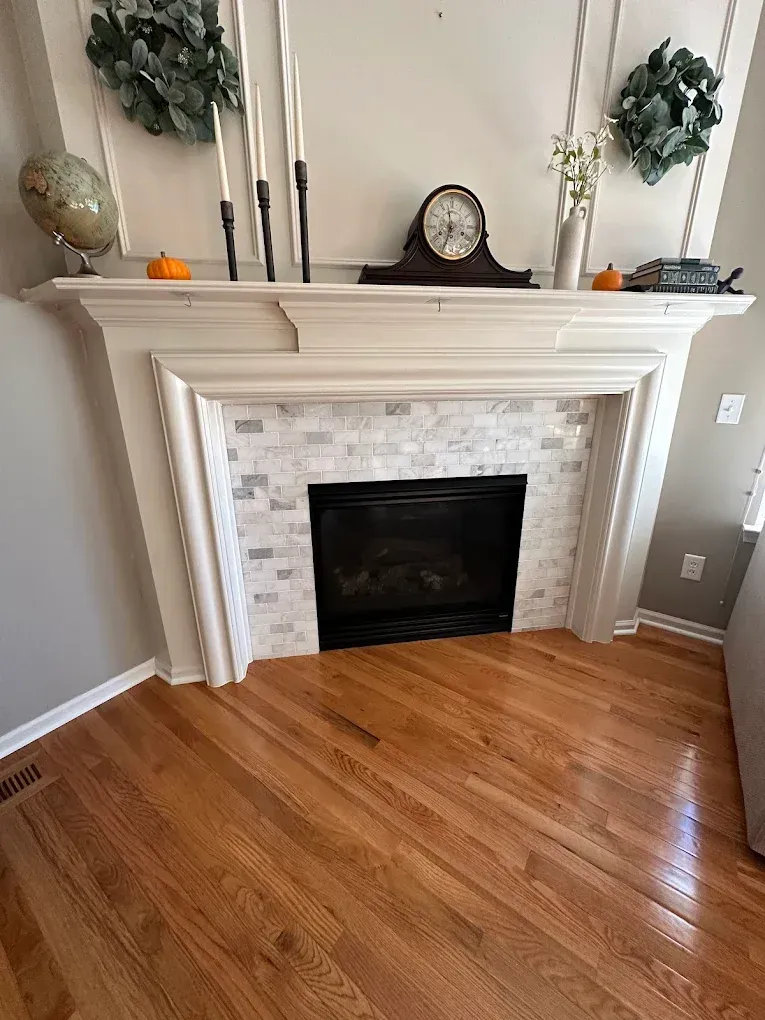 A living room with a fireplace and a clock on the mantle.