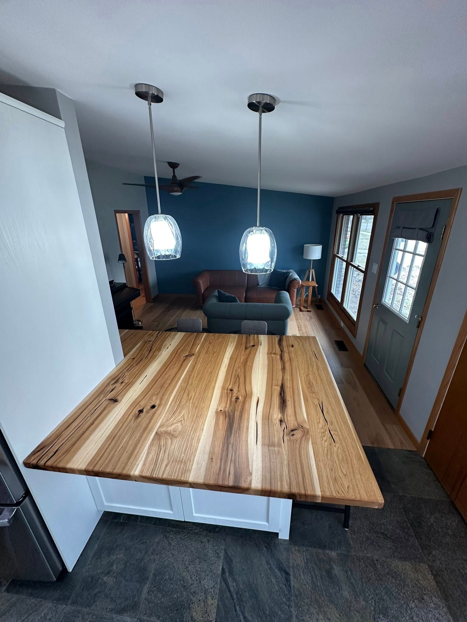 A kitchen with a wooden table and a living room in the background.