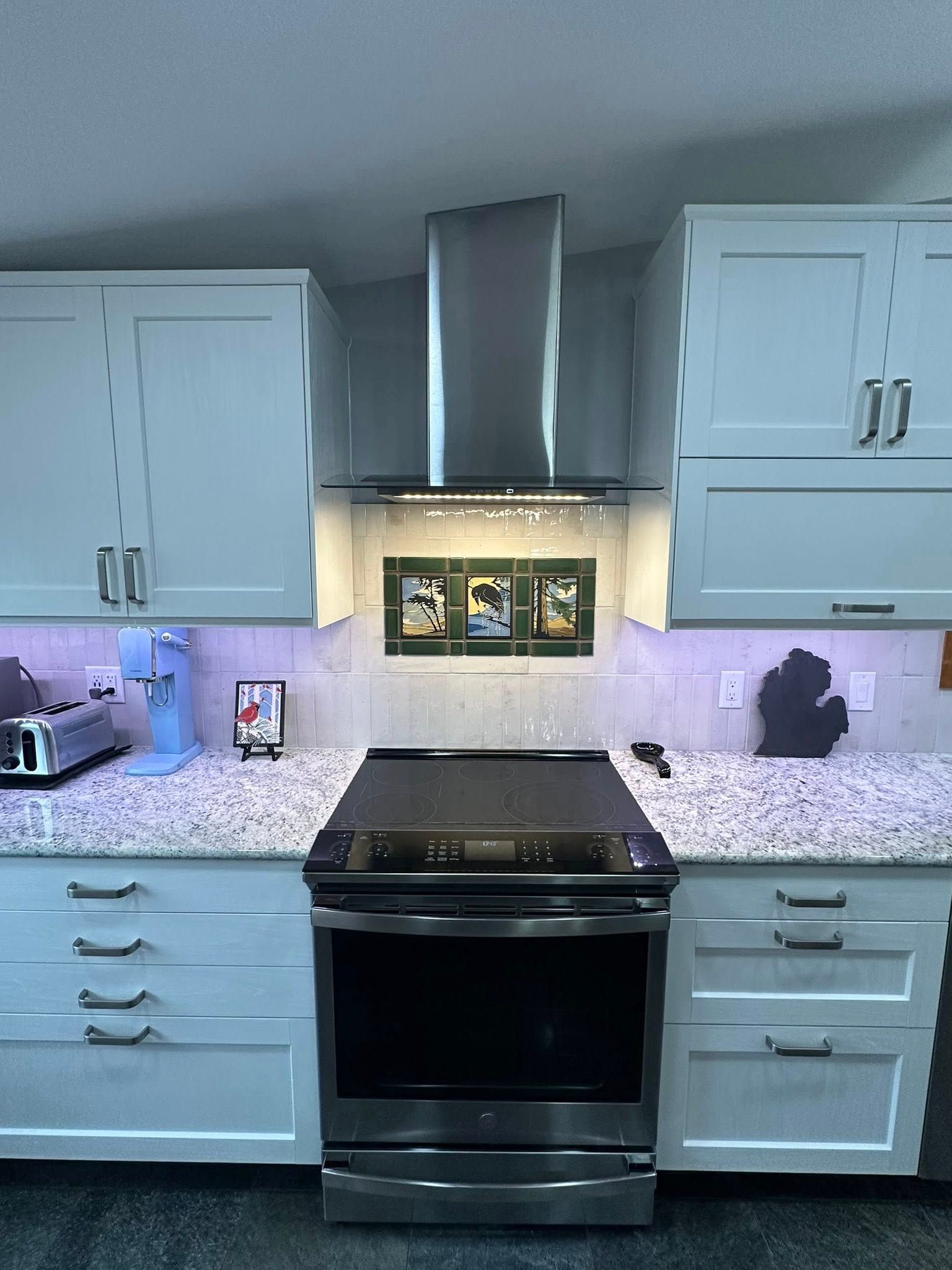 A kitchen with white cabinets , stainless steel appliances and granite counter tops.