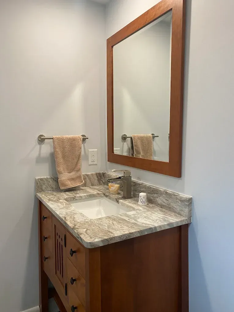 A bathroom with a sink , mirror and towel rack.