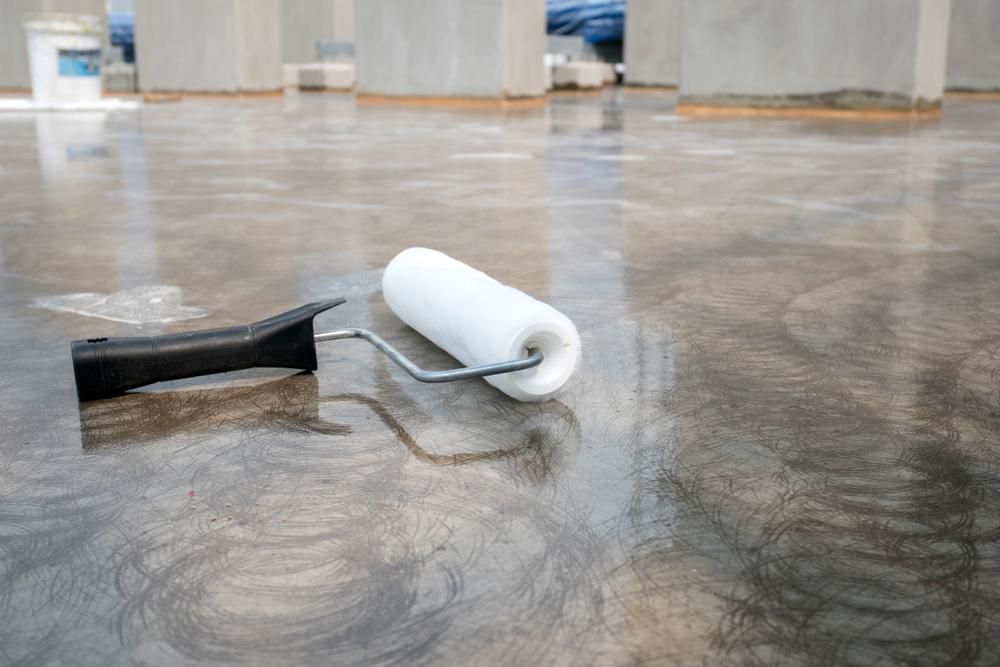 A Paint Roller Is Sitting on A Concrete Floor — Darren Smith Painting Pty Ltd in Rural View, QLD
