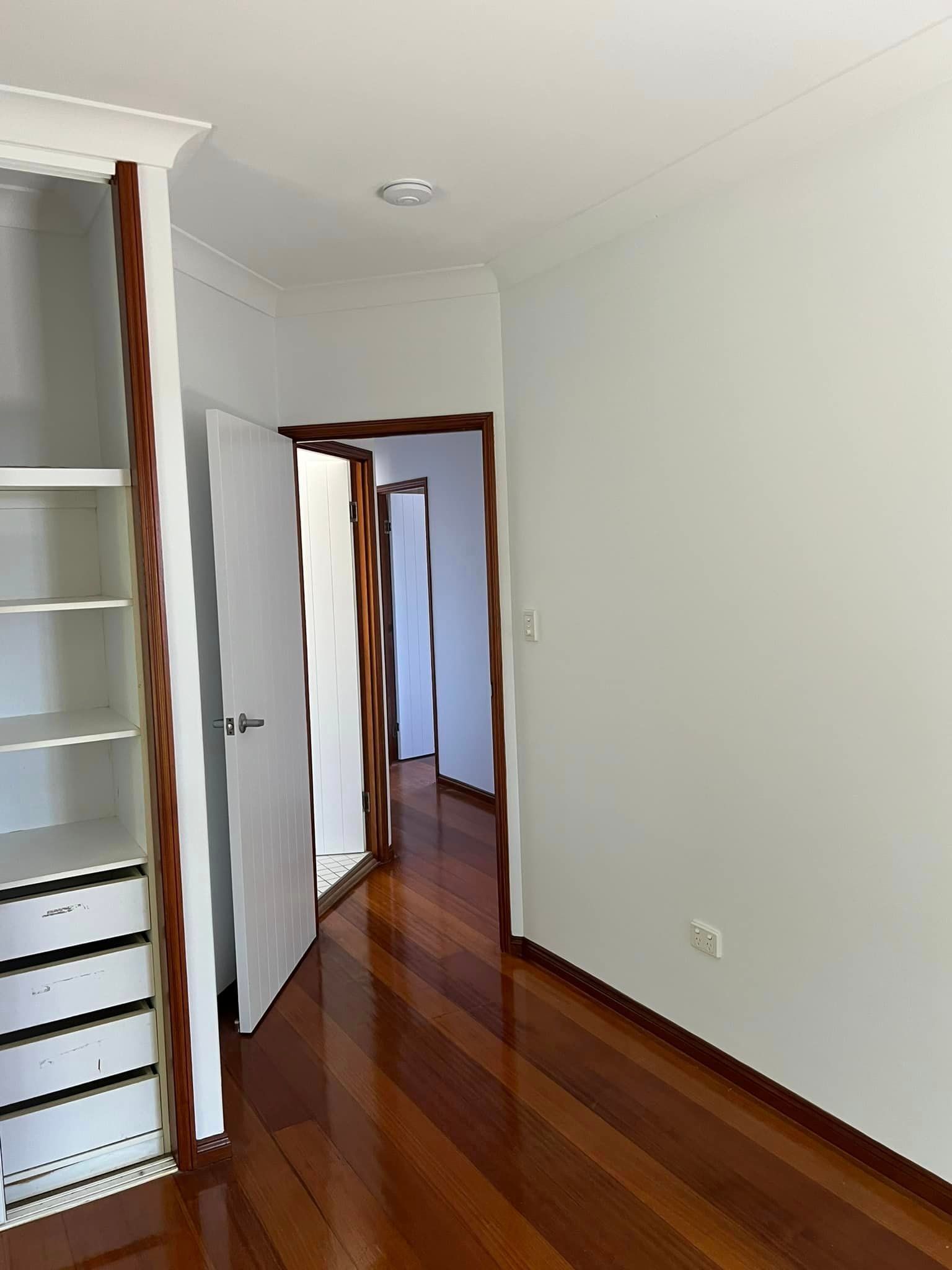 An Empty Room with Hardwood Floors and White Walls — Darren Smith Painting Pty Ltd in Rural View, QLD