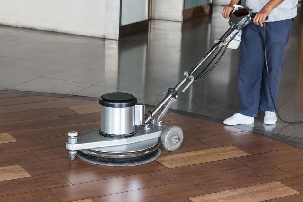 A Person Is Using a Machine to Clean a Wooden Floor — Darren Smith Painting Pty Ltd in Mirani, QLD
