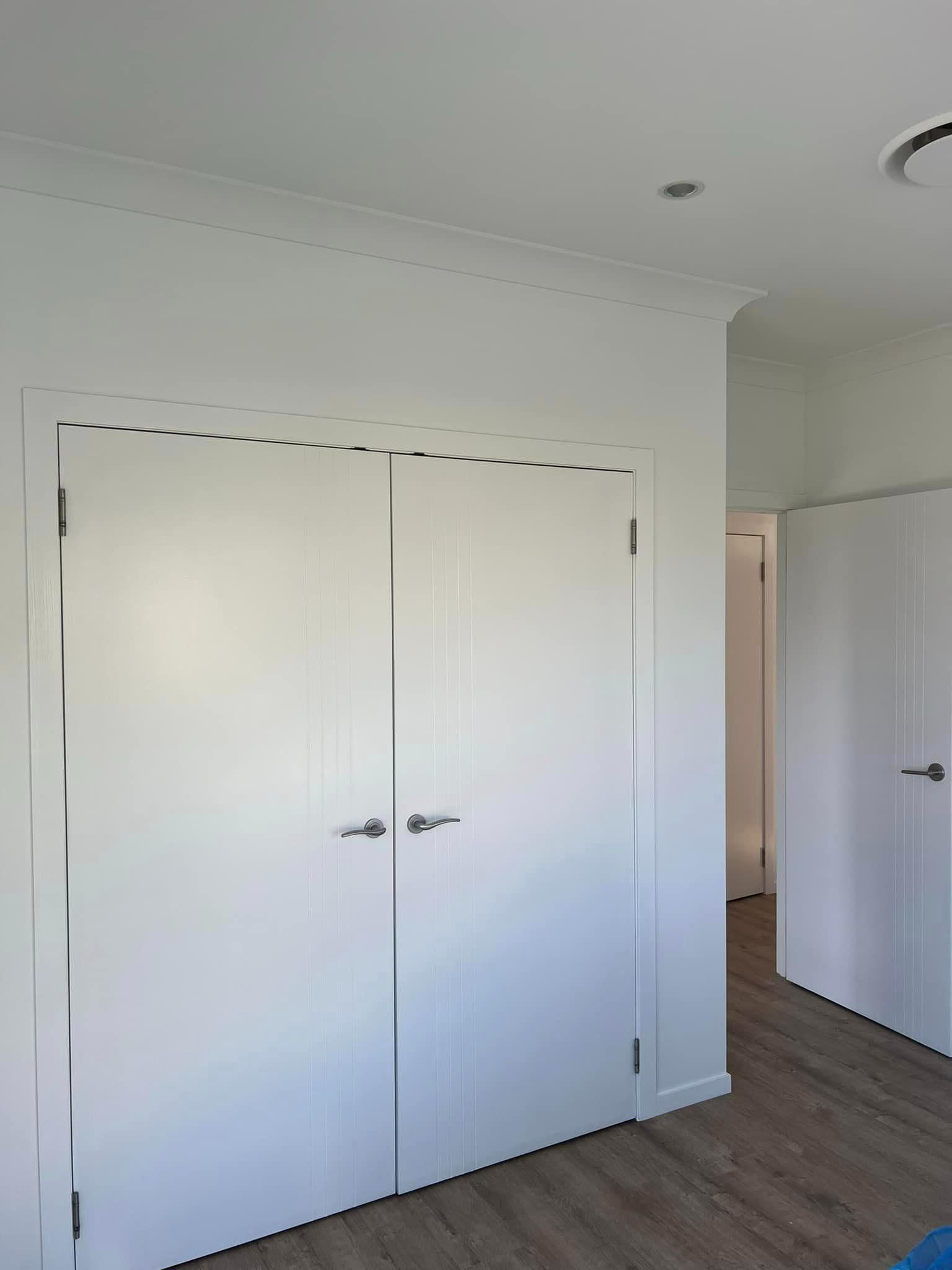 A Bedroom with A Lot of White Doors and A Wooden Floor — Darren Smith Painting Pty Ltd in Mirani, QLD
