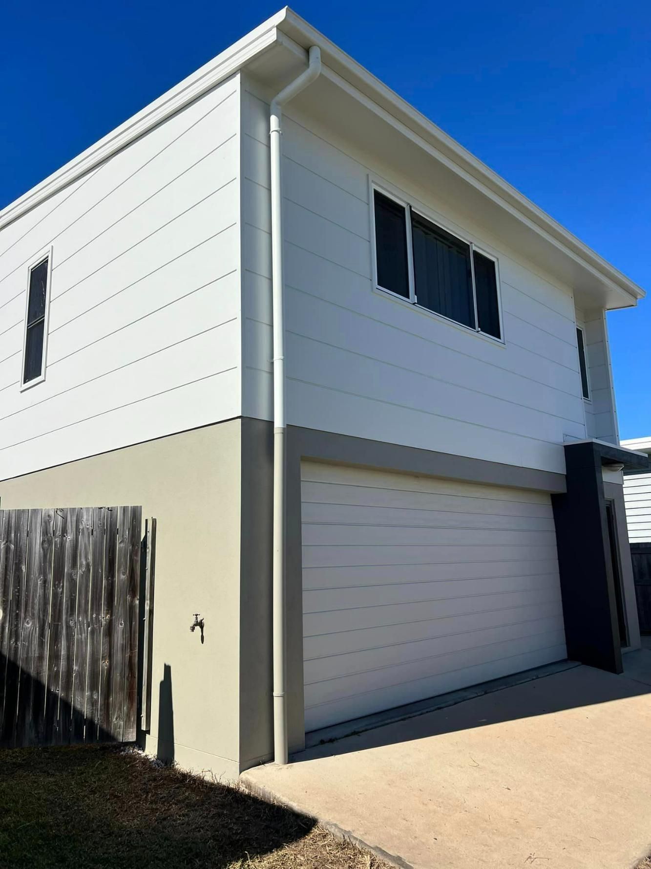 A White House with A Garage Door and A Wooden Fence — Darren Smith Painting Pty Ltd in Rural View, QLD