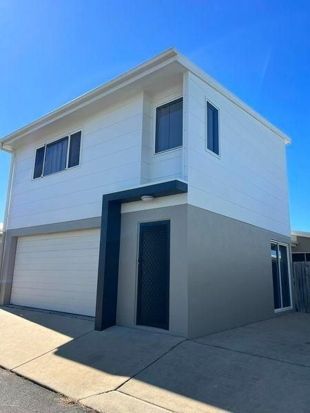 A white house with a garage and a blue sky in the background