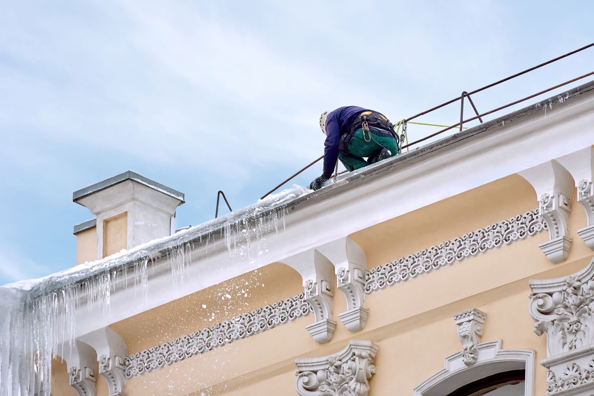Orange snowblower clearing snow from a road under a partly cloudy sky.