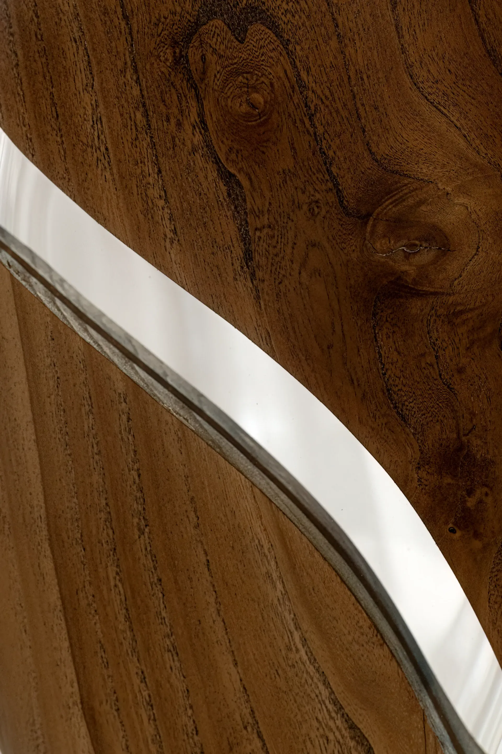 Dettaglio della lampada scultura in resina epossidica e legno. Si notano la texture del legno e la lucentezza della resina. La luce emessa dalla lampada crea un'interazione suggestiva con i materiali. Opera di Guerino Rusconi