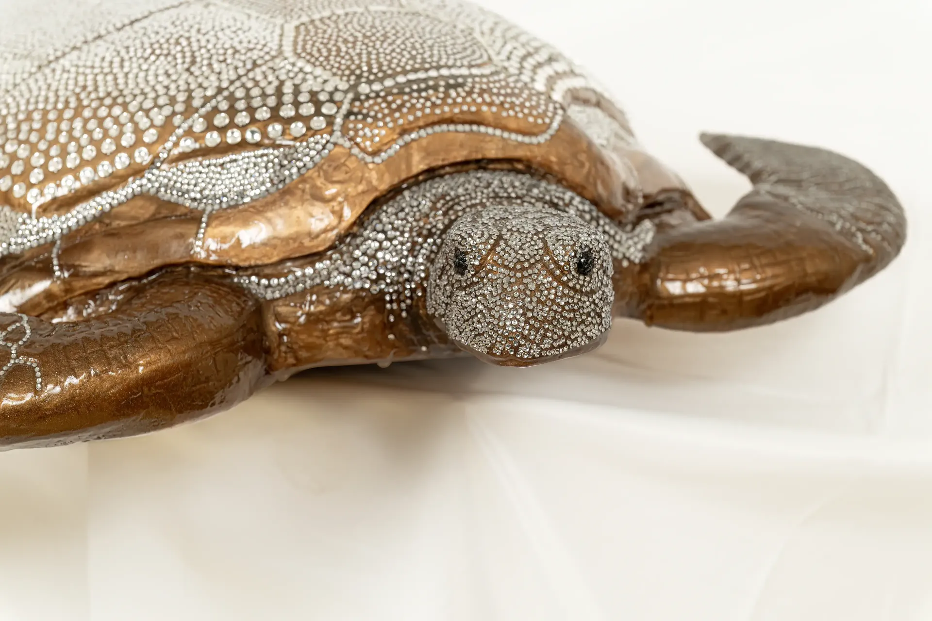 Dettaglio ravvicinato della scultura unica in resina epossidica e legno con inclusioni di vetro brillante raffigurante una tartaruga. Il dettaglio si concentra sulla complessa combinazione di resina, legno e le inclusioni di vetro brillante che creano un effetto scintillante.