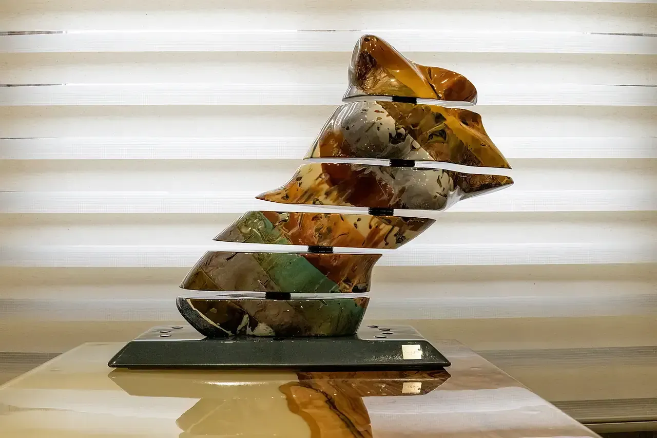 Scultura cinetica in resina raffigurante un torso femminile suddiviso in sezioni orizzontali mobili tramite perni metallici. Le sezioni ruotano, creando configurazioni multiple. Opera di Guerino Rusconi. L'opera esplora il concetto di 'arte in divenire', caratteristico dello stile dell'artista.