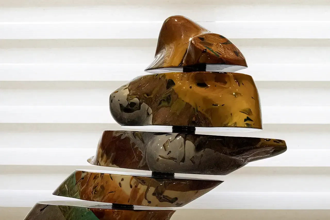 Scultura in resina epossidica e perni metallici suddivisa in sezioni mobili o rotanti, multicolore con tonalità terrose e accenti turchese e verde acqua.