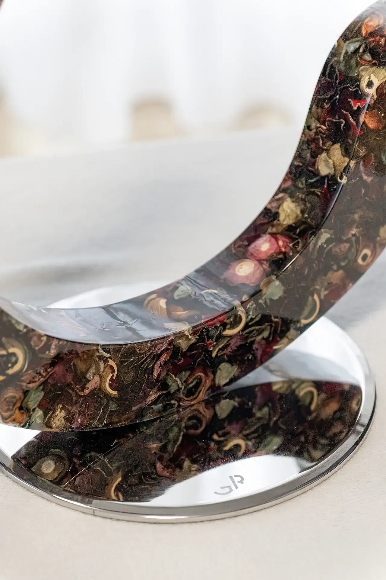 Scultura in resina epossidica con inclusioni di fiori essiccati multicolore, raffigurante una forma organica allungata. Opera unica di Guerino Rusconi.