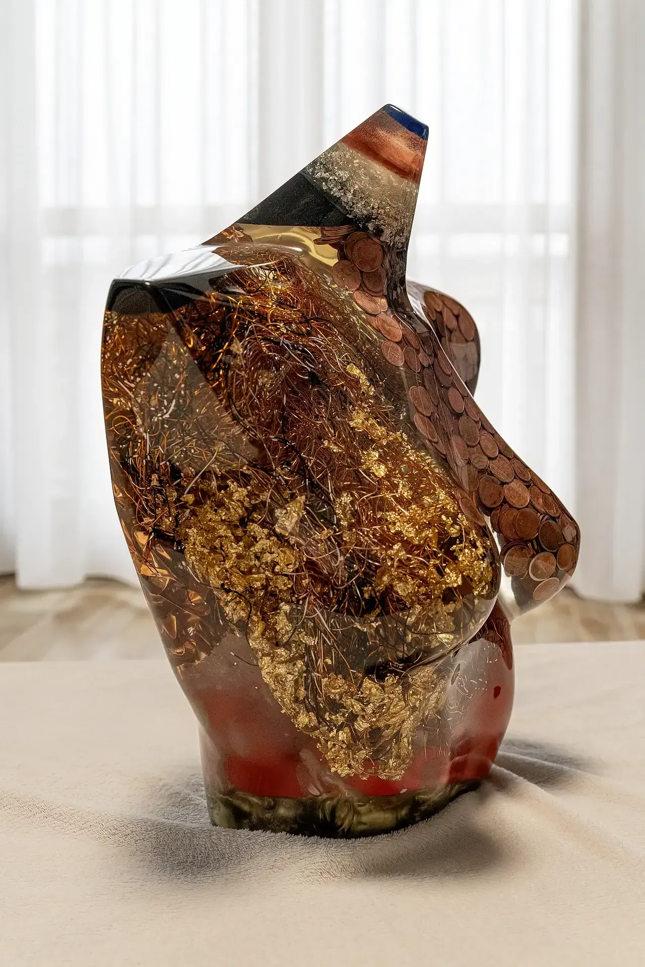 Scultura in resina, fili di alluminio, foglie d'oro e monete color rame di torso femminile vista a tre quarti. La curvatura del busto in resina epossidica trasparente mette in risalto la disposizione interna degli elementi decorativi. Opera unica di Guerino Rusconi.