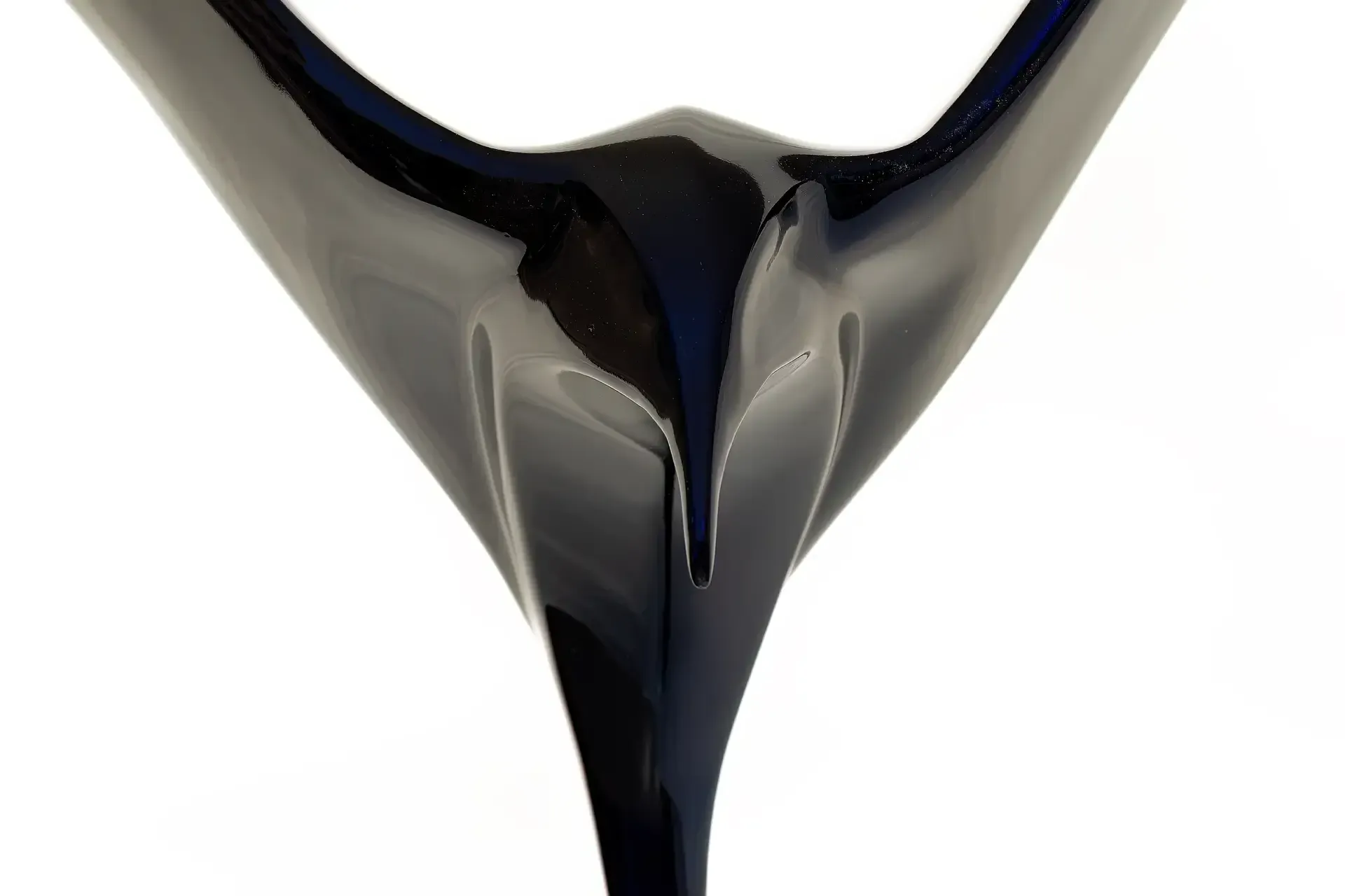 Dettaglio ravvicinato di una scultura in resina epossidica blu lucida raffigurante un gabbiano stilizzato. Opera dell'artista e artigiano Guerino Rusconi. La superficie riflettente presenta giochi di luce e ombre. Fondo bianco uniforme.