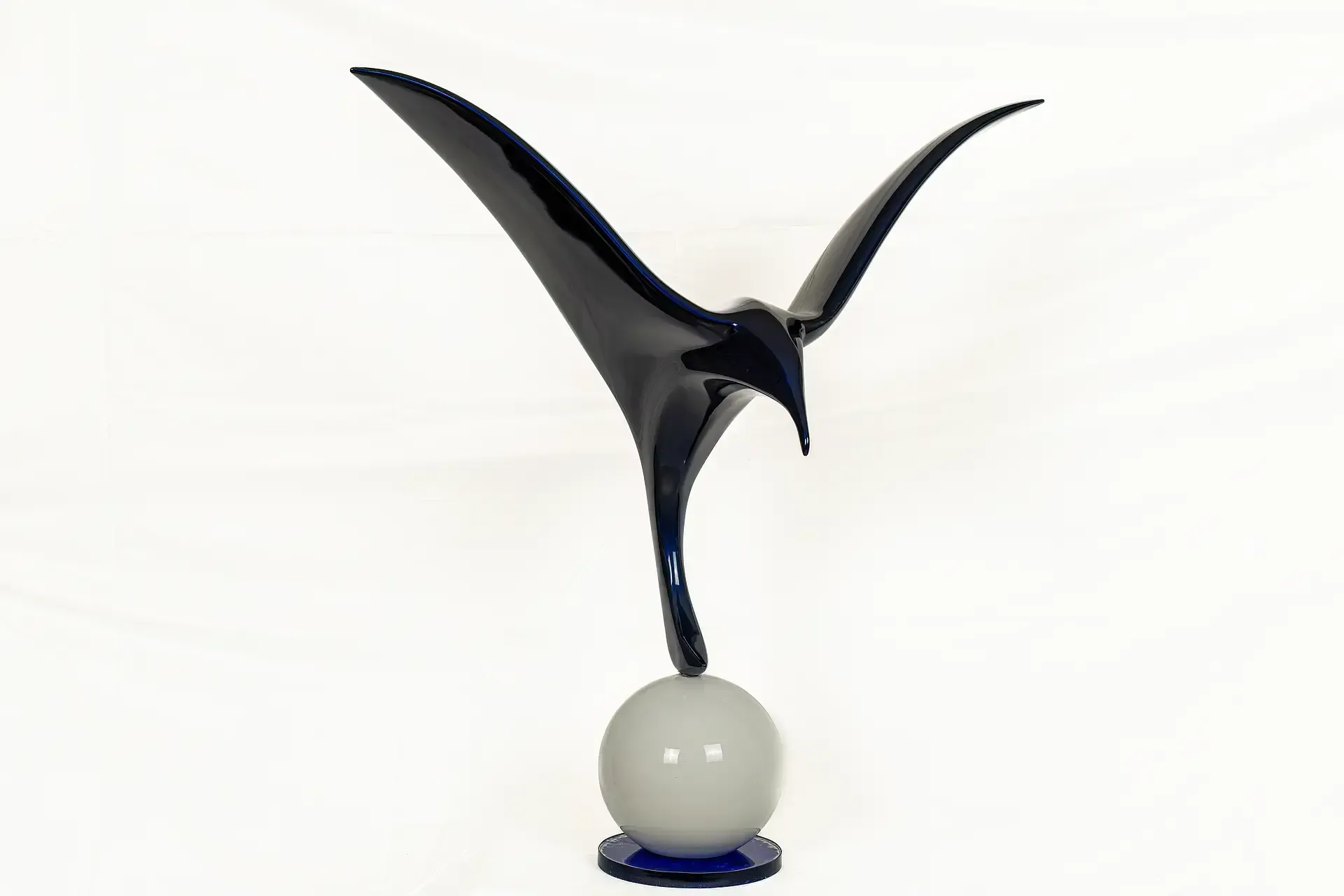 Scultura in resina epossidica blu lucida raffigurante un gabbiano stilizzato in volo, la superficie riflettente presenta giochi di luce e ombre. Opera dell'artista e artigiano Guerino Rusconi.