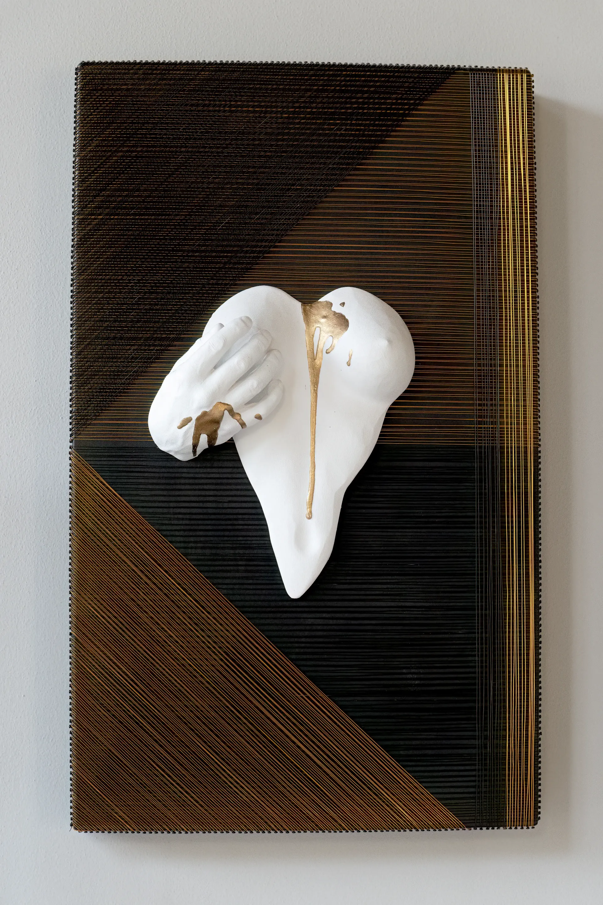 Scultura su pannello ligneo di Guerino Rusconi realizzata in resina, fili di alluminio e gesso ceramico. L'opera presenta una forma organica di seni femminili in gesso ceramico. Lo sfondo presenta una trama geometrica di fili di alluminio neri e marroni.