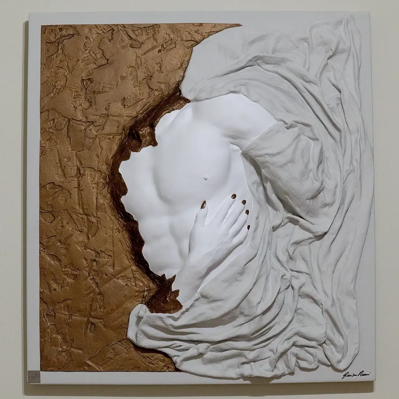 Scultura tridimensionale con tecnica mista. L'opera raffigura un torso maschile in gesso ceramico bianco, parzialmente coperto da un drappeggio in tessuto resinato bianco. Il torso emerge da una superficie con texture materica nei toni del marrone e dell'oro. Una mano è appoggiata sul petto. Opera di Guerino Rusconi.