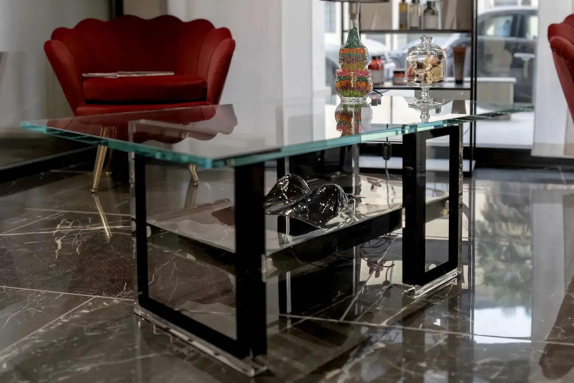 Tavolino di design in vetro e resina trasparente con ripiano inferiore. Sul ripiano è posizionata una scultura tridimensionale in resina nera lucida raffigurante seni femminili. Opera artistica di Guerino Rusconi.