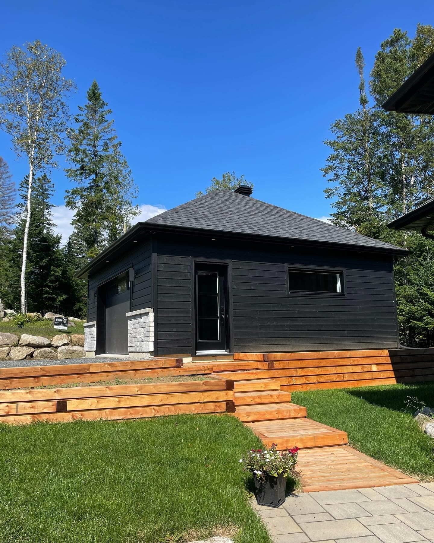 An interior view of a room under construction, showing wooden framing, exposed rafters, and pink insulation in the walls.