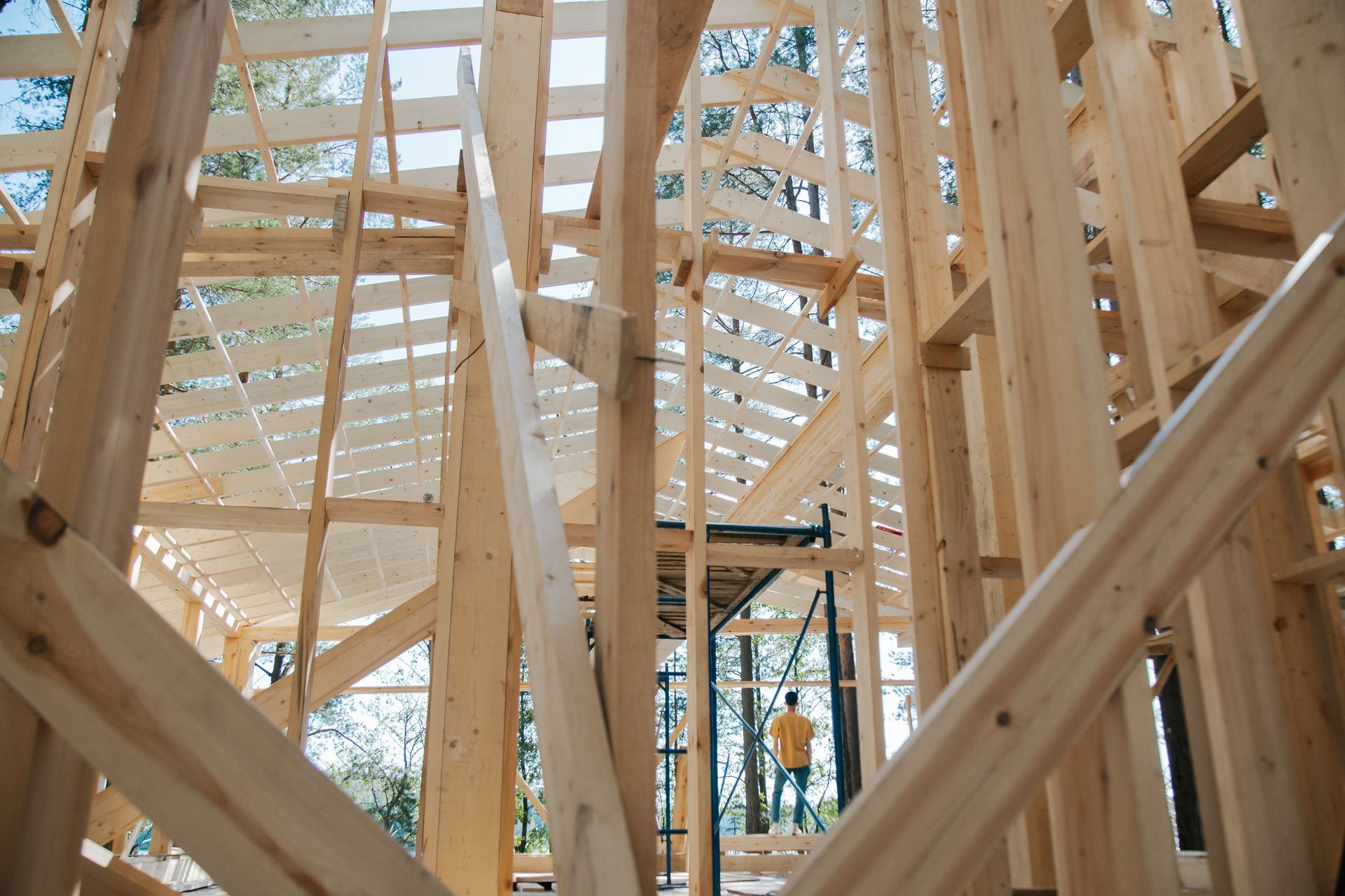 Wooden house frame under construction with beams and roof trusses visible inside