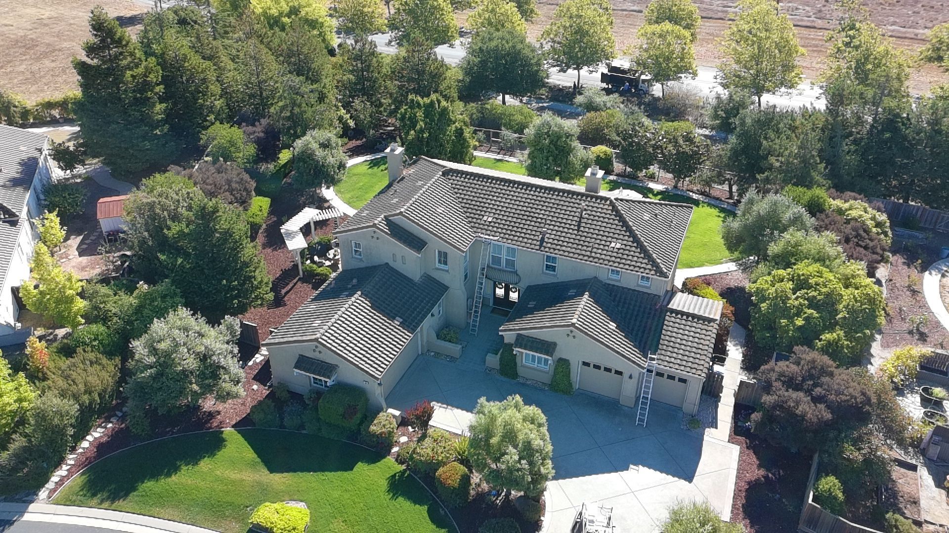 An aerial view of a large house with a tiled roof surrounded by trees and landscaping.