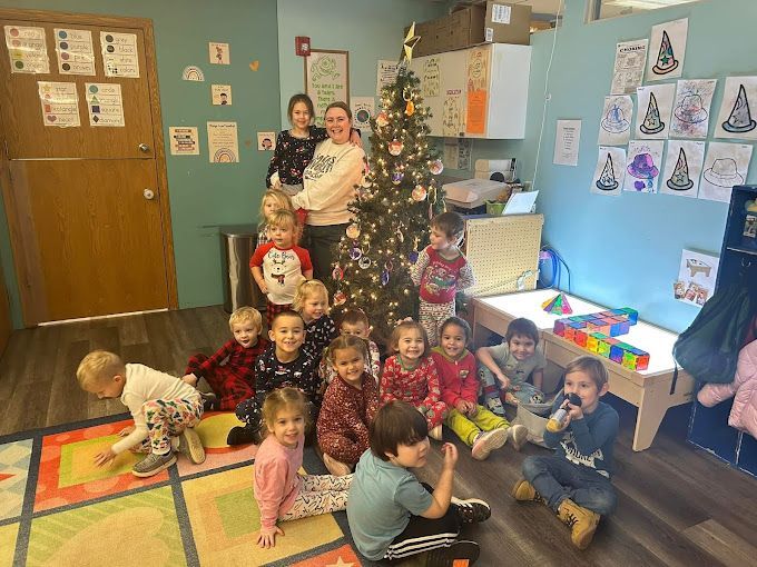 A group of children are sitting around a christmas tree in a room.