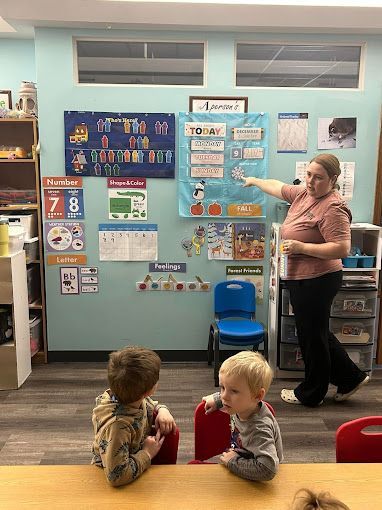 A woman is teaching two young boys in a classroom.