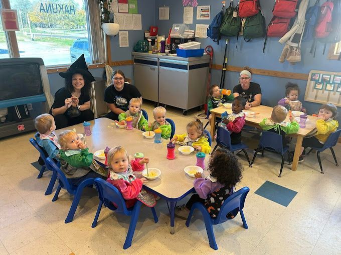 A group of children are sitting at tables in a classroom eating food.